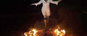 Donna che attraversa il fuoco durante una camminata sui carboni ardenti in un rituale di meditazione esperienziale